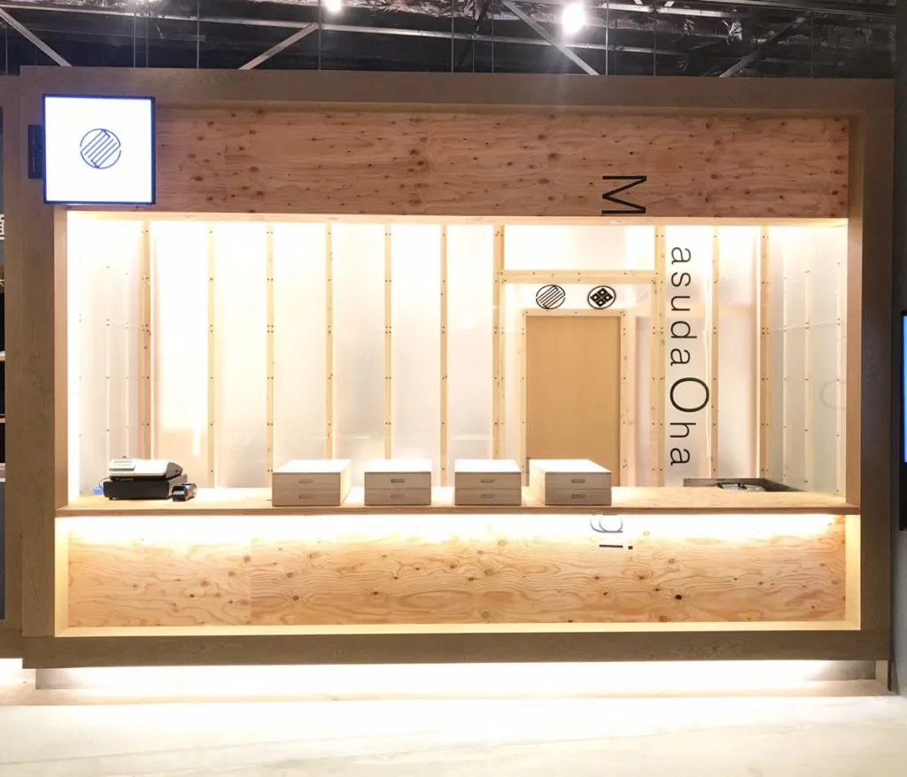 商業施設のフードコート内の和菓子店。無塗装の木のカウンターとアクリル板の壁（家物語グループ札幌オフィスの施工例）